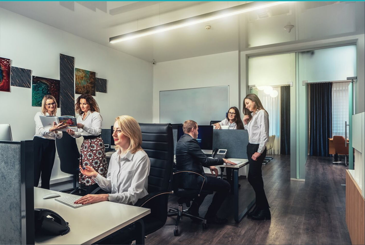 Сотрудники DION ART STUDIO работают в открытом офисном пространстве, групповые обсуждения за рабочими столами, современный интерьер с произведениями искусства на стенах.